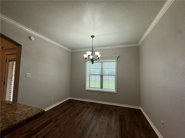 an empty room with wooden floor cabinet and windows