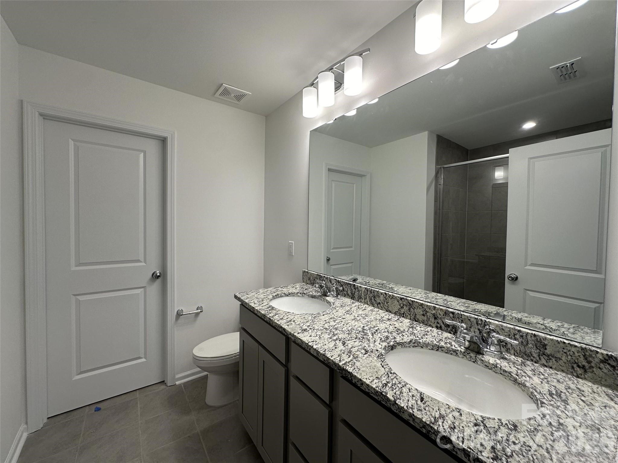 1872 Teachers House Road Northwest Concord, NC 28027 - Photo 10 of 14 a bathroom with a granite countertop sink a toilet and a large mirror