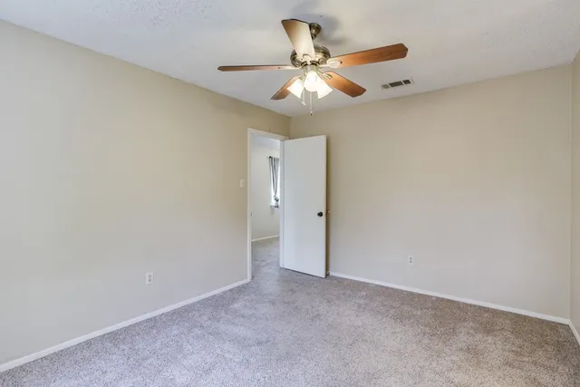 an empty room with a chandelier fan and a ceiling fan