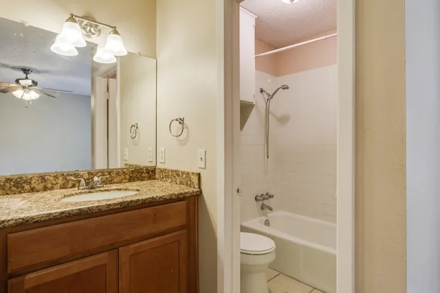 a bathroom with a granite countertop sink toilet and shower