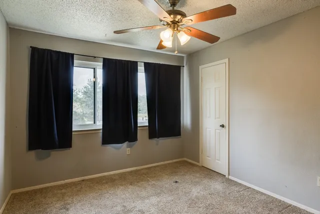 an empty room with windows and fan