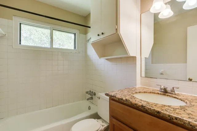 a bathroom with a granite countertop sink toilet and a bathtub
