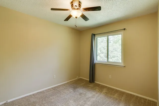 an empty room with a window and a fan