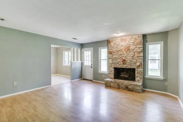 an empty room with windows fireplace and wooden floor