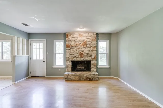 an empty room with a fireplace and windows