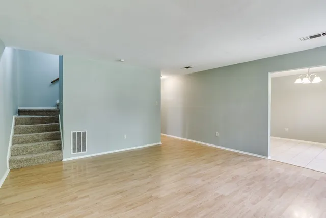 a view of an empty room with wooden floor and stairs