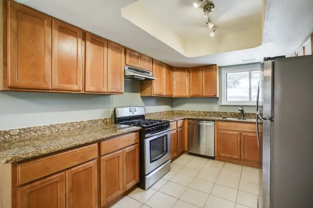 a kitchen with stainless steel appliances granite countertop a stove sink and cabinets