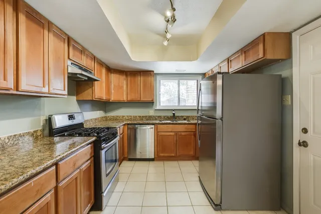 a kitchen with stainless steel appliances granite countertop a refrigerator a sink dishwasher a stove with wooden cabinets and floor