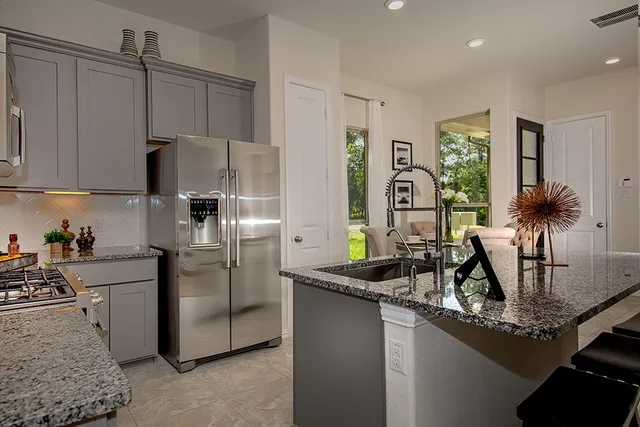 a kitchen with stainless steel appliances granite countertop a sink a stove and a refrigerator