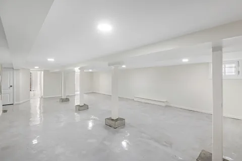 a view of an empty room with kitchen and window