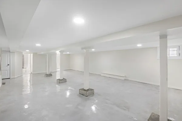 a view of an empty room with kitchen and window