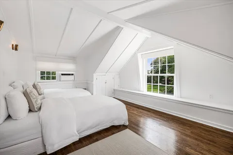 a large bed sitting in a bedroom next to a window and a potted plant