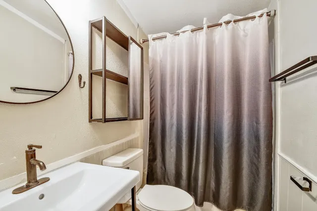 a bathroom with a sink a toilet and a mirror