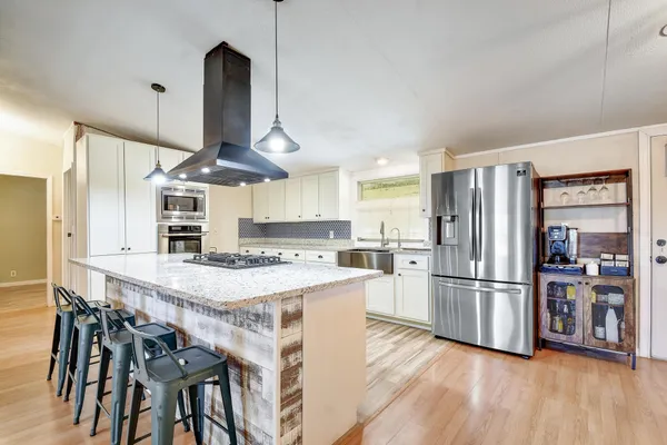 a kitchen with stainless steel appliances a refrigerator a stove a sink and a dining table with wooden floor