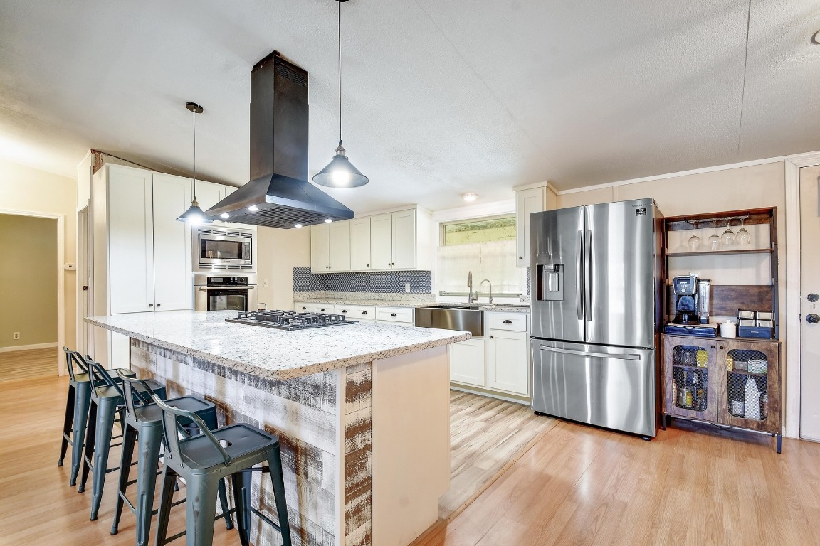 17398 Benton City Road Von Ormy, TX 78073 - Photo 9 of 25 a kitchen with stainless steel appliances a refrigerator a stove a sink and a dining table with wooden floor