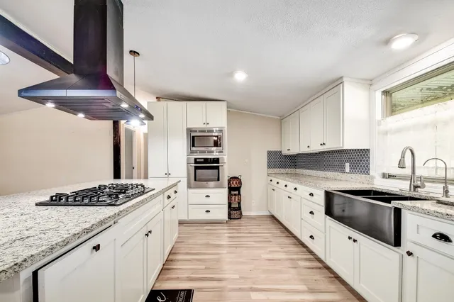 a large kitchen with stainless steel appliances kitchen island granite countertop a lot of counter space and wooden floors