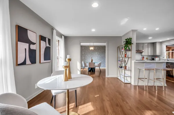 a living room with stainless steel appliances furniture a dining table and kitchen view