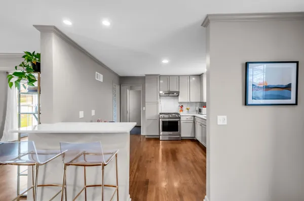 a kitchen with stainless steel appliances a stove a refrigerator a oven a dining table and chairs with wooden floor