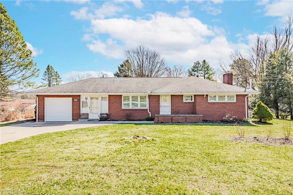 a house that has a big yard with plants and trees in front of it