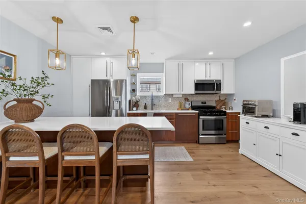 a kitchen with stainless steel appliances kitchen island granite countertop a refrigerator a stove a sink dishwasher a dining table and chairs with wooden floor