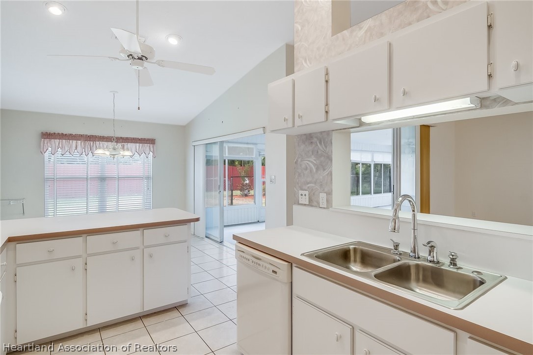 246 Tangerine Road Lake Placid, FL 33852 - Photo 13 of 36 a kitchen with a sink dishwasher and white cabinets with wooden floor
