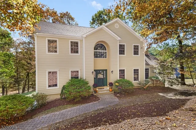 a view of a white house next to a yard with large trees