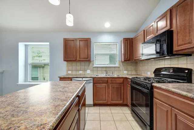 a kitchen with stainless steel appliances granite countertop a sink a stove a refrigerator and a microwave