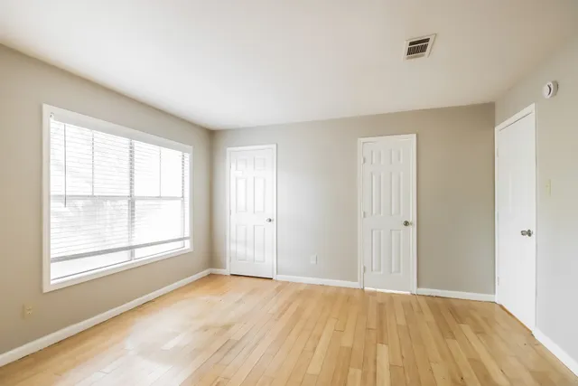 a view of an empty room with wooden floor and a window