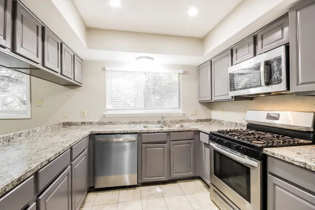 a kitchen with stainless steel appliances granite countertop white cabinets a sink and a stove