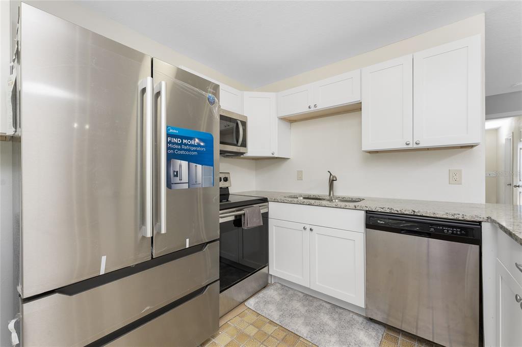 5041 North Beach Road, Unit 2A AND 2B Englewood, FL 34223 - Photo 8 of 90 a kitchen with stainless steel appliances granite countertop a refrigerator sink and white cabinets