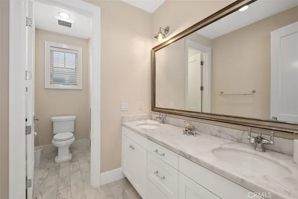 a bathroom with a granite countertop sink a toilet and a mirror