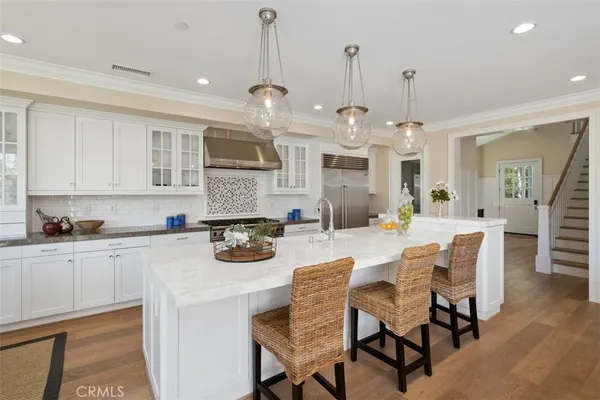 a kitchen with stainless steel appliances kitchen island granite countertop a table chairs and a white cabinets