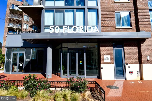 a view of a brick house with large windows and plants