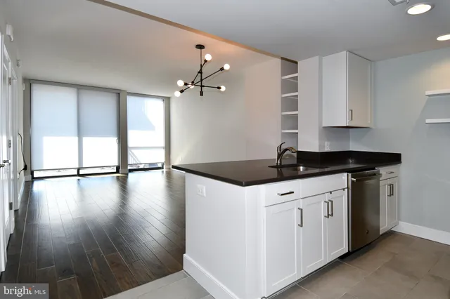 a kitchen that has a sink a microwave and wooden floor