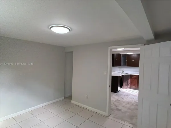 a view of an empty room and a kitchen