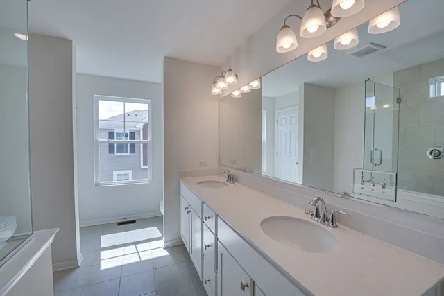 a bathroom with double vanity sinks a toilet a shower a vanity and a mirror