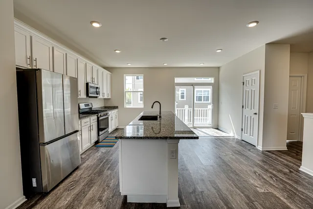 a kitchen with granite countertop a refrigerator stove top oven and sink