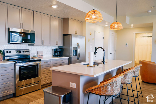 961 West Akoya Pearl Road, Unit 201 St. George, UT 84790 - Photo 15 of 67 Kitchen featuring stainless steel appliances, light wood-type flooring, light countertops, a breakfast bar, and a textured ceiling