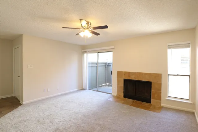 an empty room with windows and fireplace