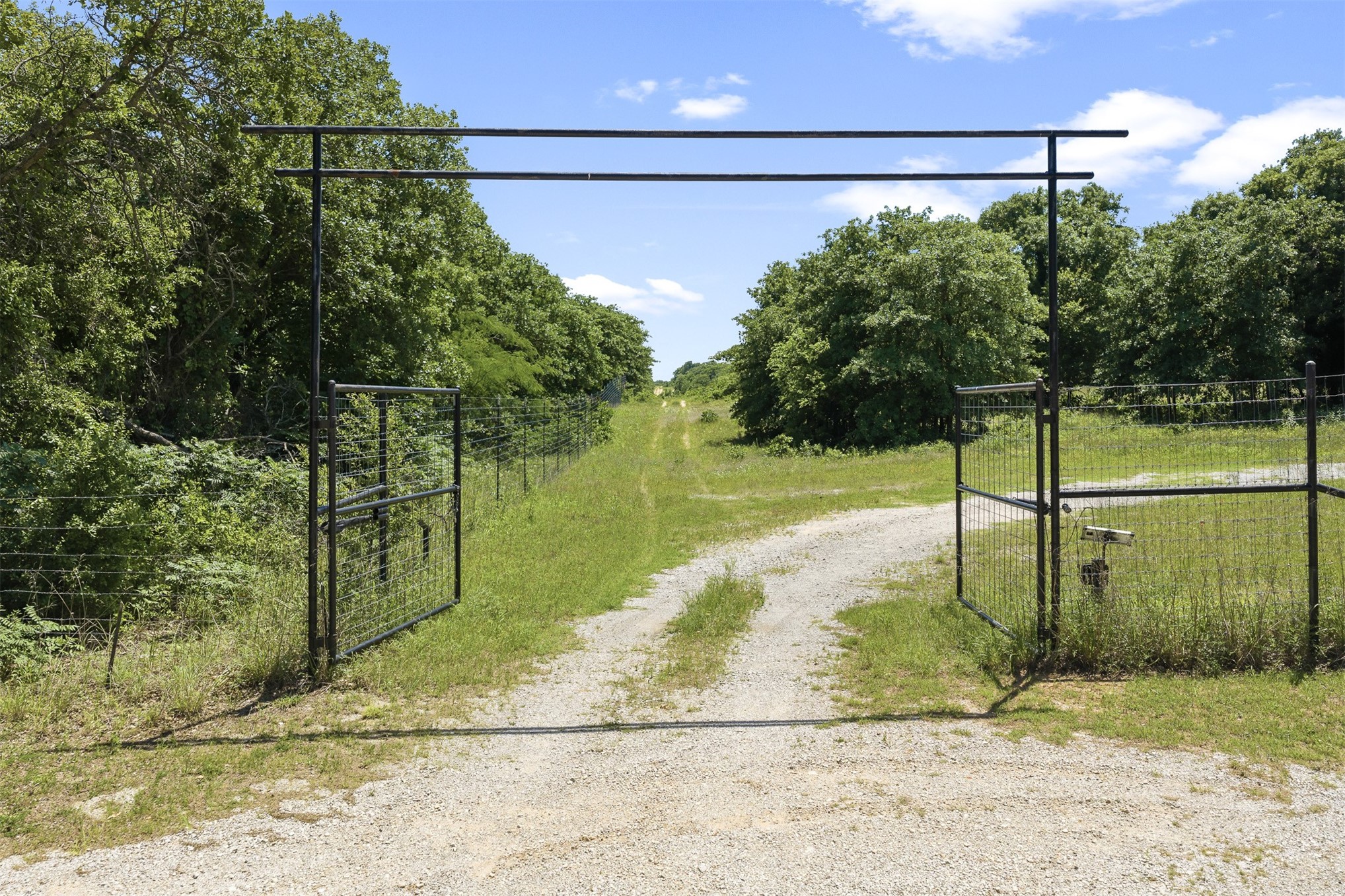 831 Barrons Ridge Wilson, OK 73463 - Photo 5 of 47 Gravel driveway entry featuring a black metal gate and fence line