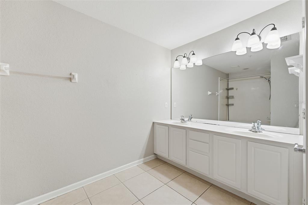 2838 Villafuerte Point, Unit 107 Orlando, FL 32835 - Photo 13 of 27 a bathroom with a double vanity sink and a mirror