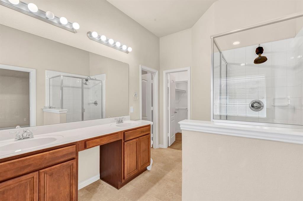 5316 Ridgeson Drive McKinney, TX 75071 - Photo 24 of 33 Bathroom featuring a dual vanity with a built-in dressing area, wood-finish cabinetry, and a spacious glass-enclosed shower with subway tile surround