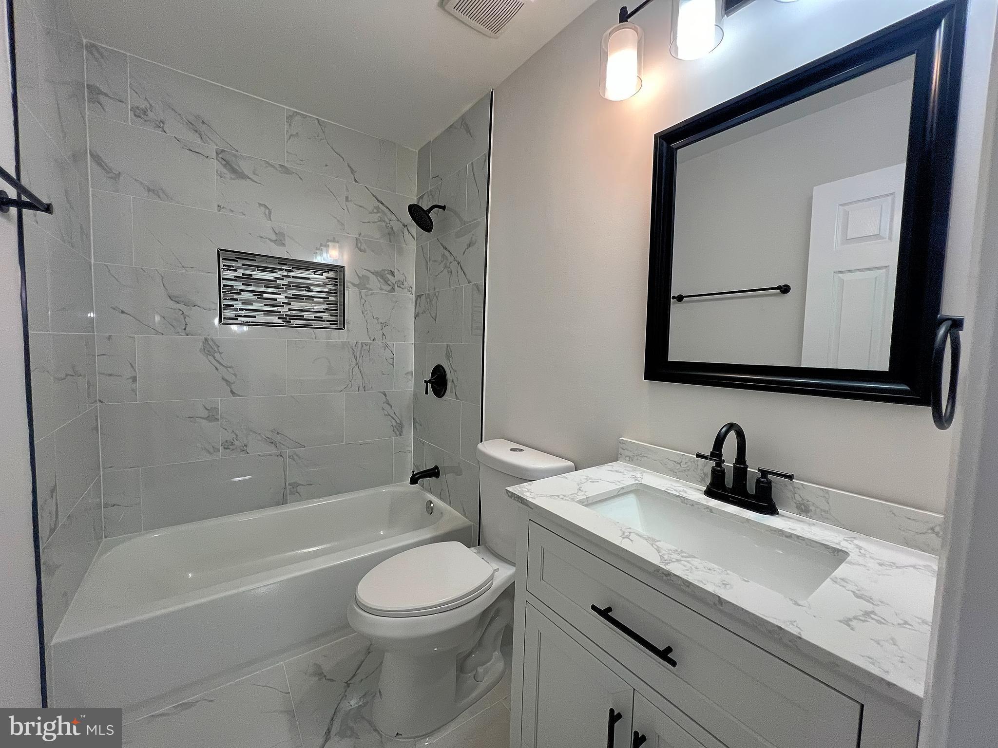 9864 Greenbriar Way Middle River, MD 21220 - Photo 15 of 17 a bathroom with a toilet a sink a bathtub and a mirror