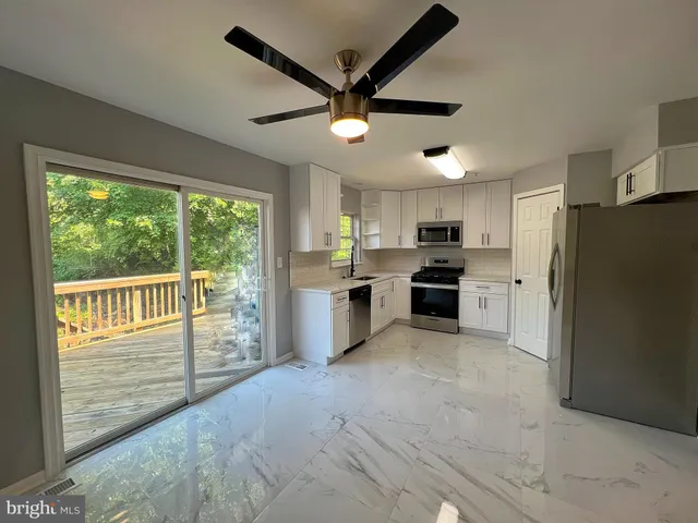 a kitchen with stainless steel appliances granite countertop a refrigerator a stove a sink and a large window