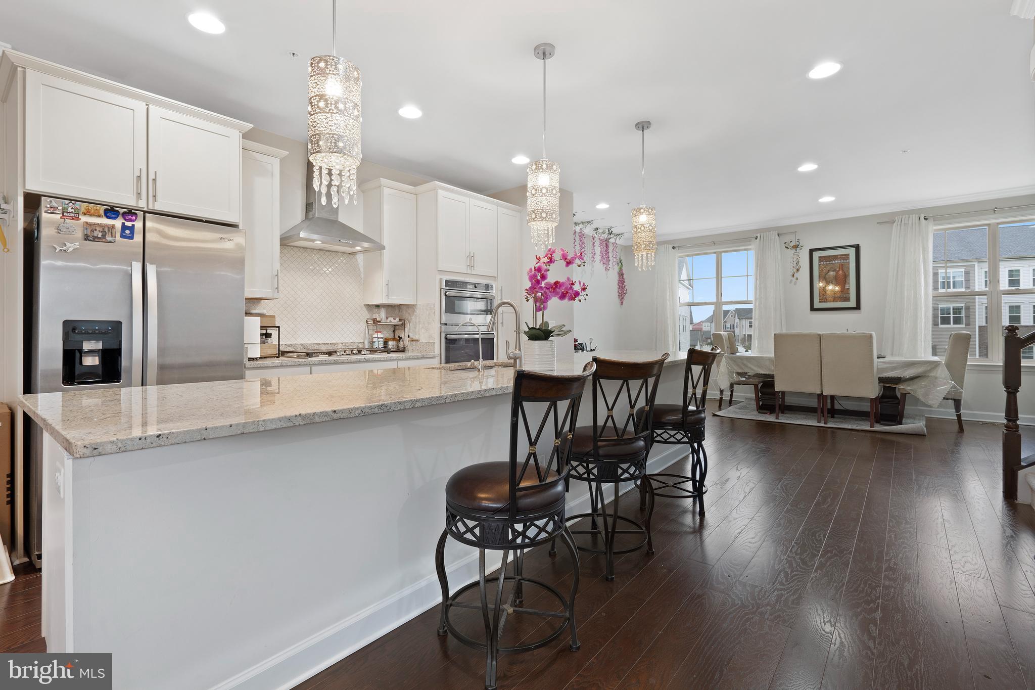 3516 Flatwoods Drive Frederick, MD 21704 - Photo 8 of 41 a kitchen with stainless steel appliances kitchen island granite countertop a table chairs refrigerator and microwave