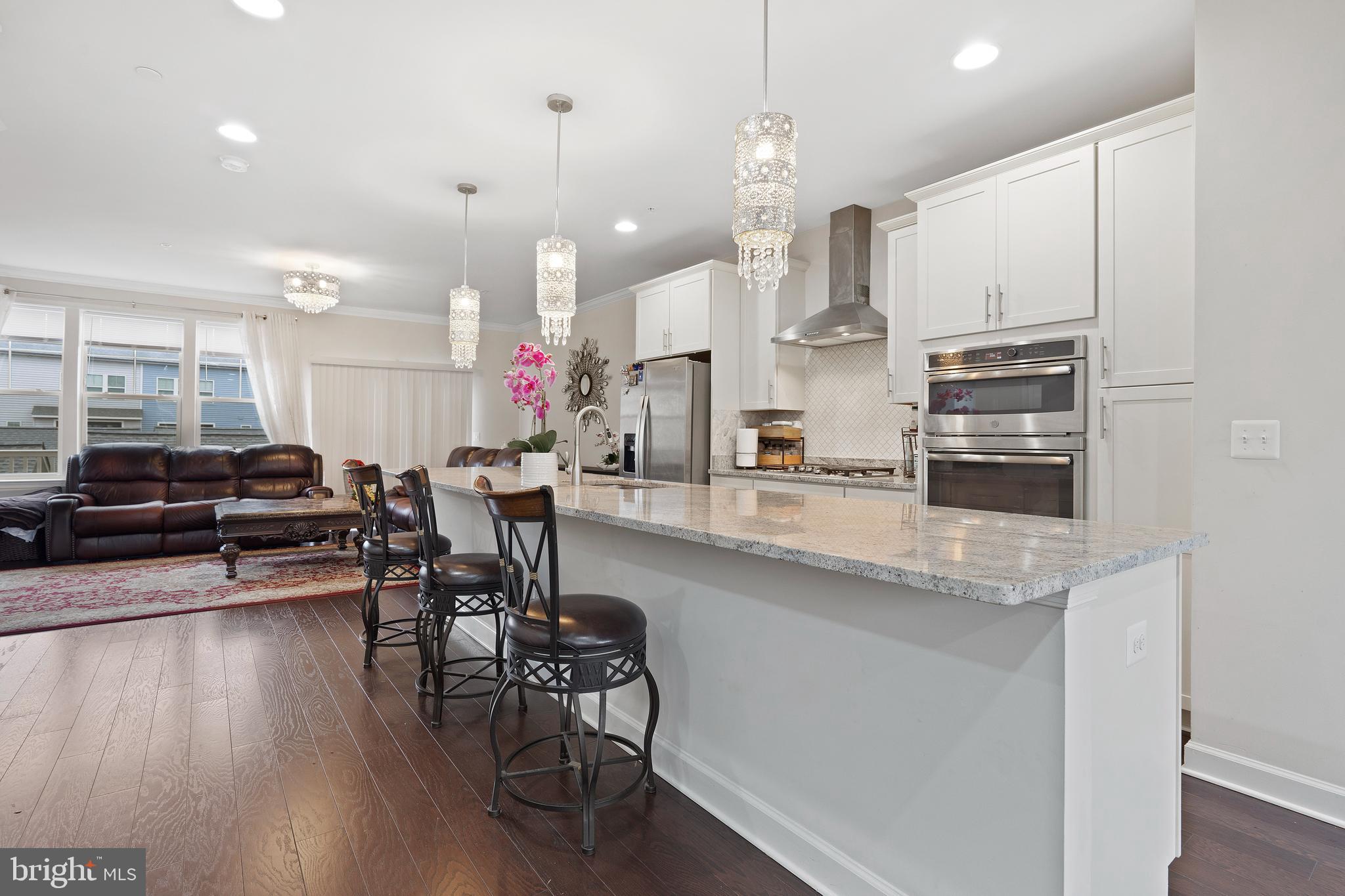 3516 Flatwoods Drive Frederick, MD 21704 - Photo 9 of 41 a kitchen with stainless steel appliances granite countertop a stove top oven a refrigerator a dining table and chairs with wooden floor