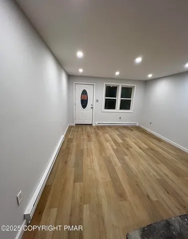 a view of an empty room with wooden floor and a window