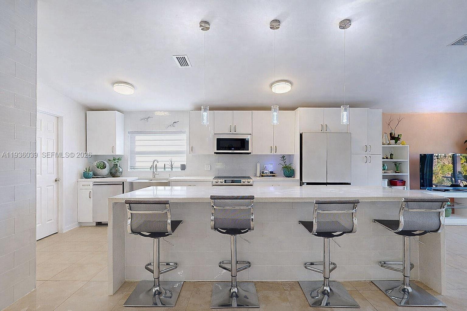 2625 40th Avenue Southeast Naples, FL 34117 - Photo 17 of 81 a kitchen with stainless steel appliances a refrigerator a stove a sink counter tops and chairs with wooden floor