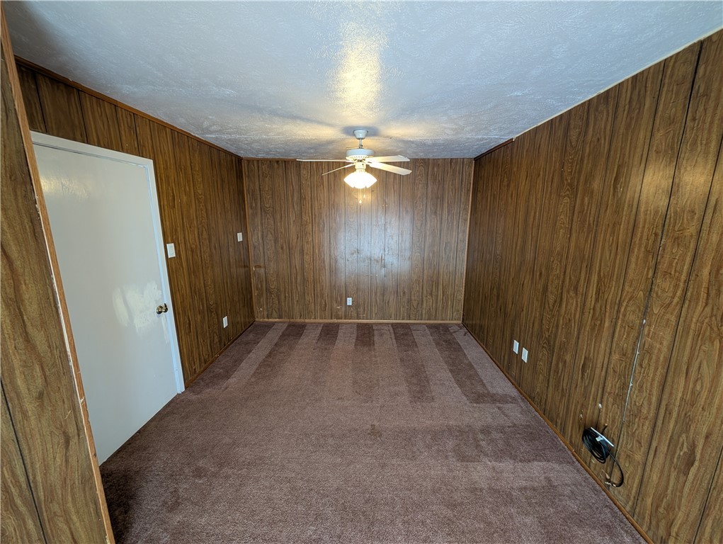 2901 Minnesota Avenue Bryan, TX 77803 - Photo 13 of 16 Unfurnished room with dark carpet, wooden walls, a textured ceiling, and ceiling fan