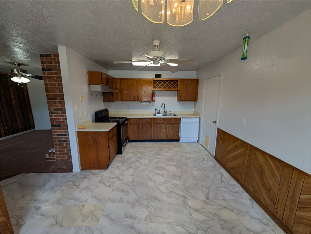 2901 Minnesota Avenue Bryan, TX 77803 - Photo 2 of 16 Kitchen featuring a ceiling fan, light countertops, black electric range oven, wood walls, and a textured ceiling